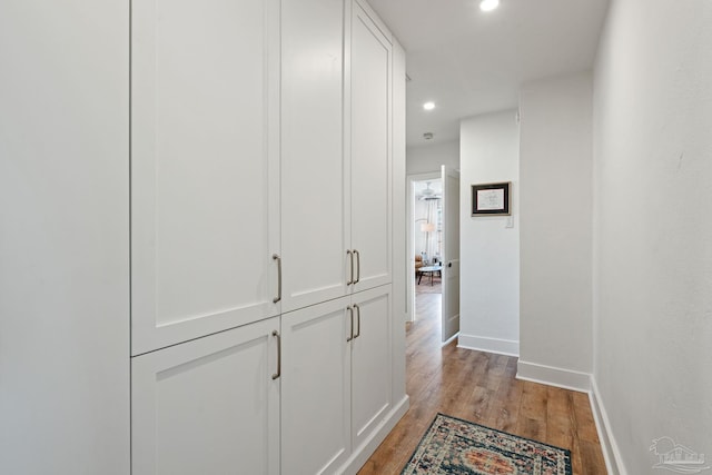 hallway featuring light wood-style floors, recessed lighting, and baseboards