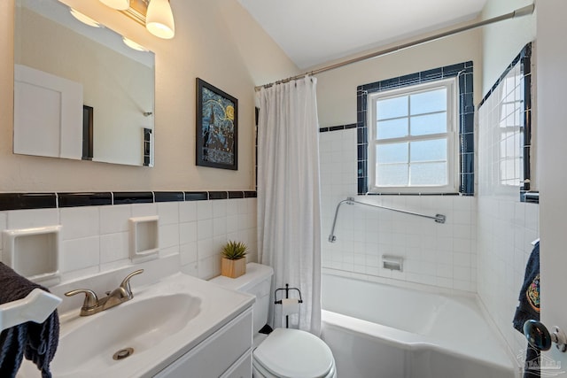 full bath featuring a wainscoted wall, tile walls, toilet, shower / bath combo, and vanity