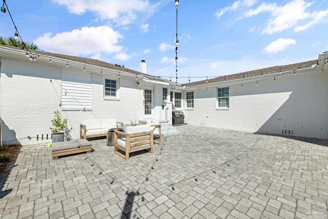 rear view of house featuring outdoor lounge area, a patio, a chimney, and brick siding