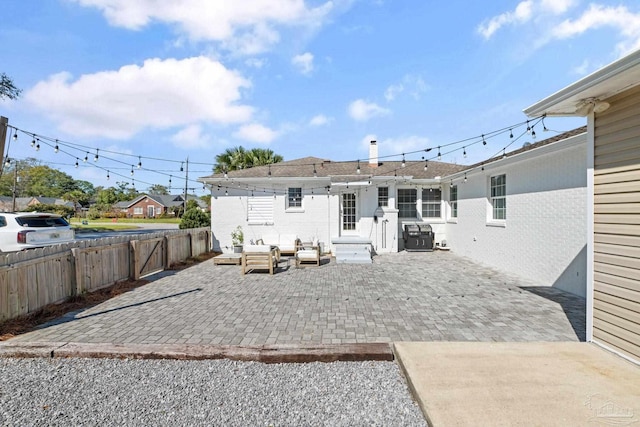 rear view of property with entry steps, brick siding, a patio area, and fence