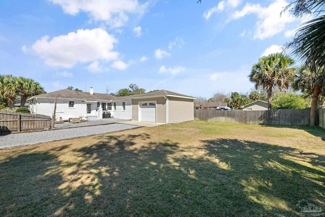 back of house with a garage, a patio area, a fenced backyard, and a lawn