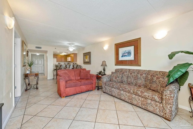 living area with light tile patterned floors, visible vents, baseboards, ceiling fan, and a textured ceiling