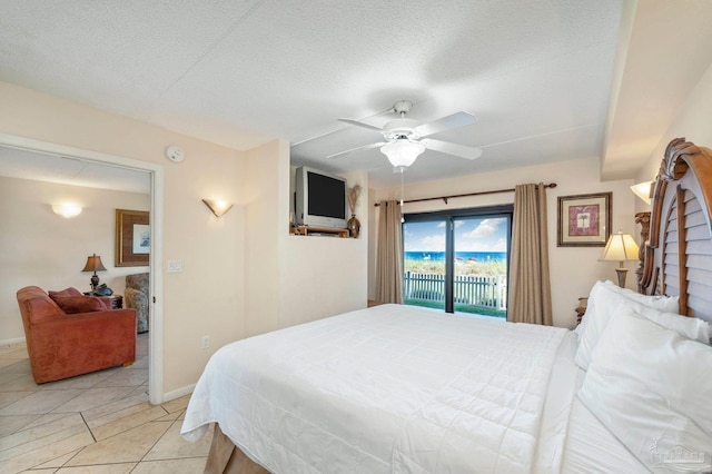 bedroom featuring a textured ceiling, light tile patterned floors, a ceiling fan, baseboards, and access to exterior