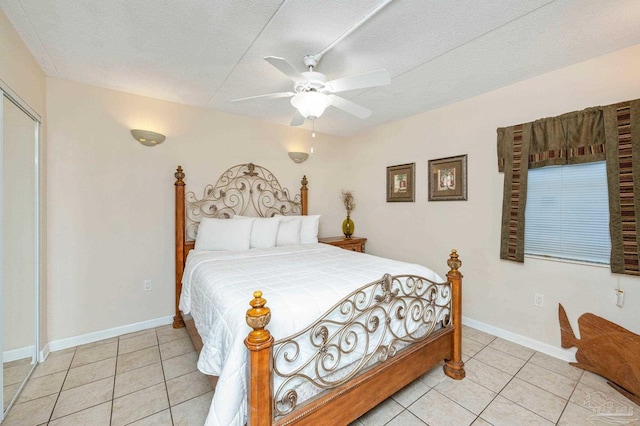 bedroom with light tile patterned floors, a textured ceiling, baseboards, and a ceiling fan