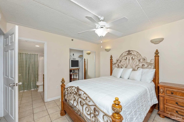 bedroom with light tile patterned floors, a textured ceiling, ensuite bath, and baseboards