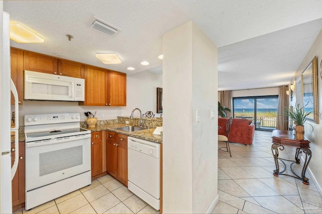 kitchen with white appliances, sink, light stone counters, a textured ceiling, and light tile patterned floors