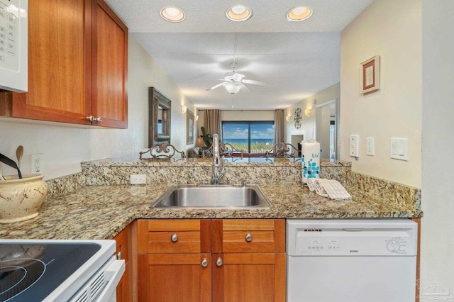 kitchen featuring white appliances, brown cabinets, and a sink