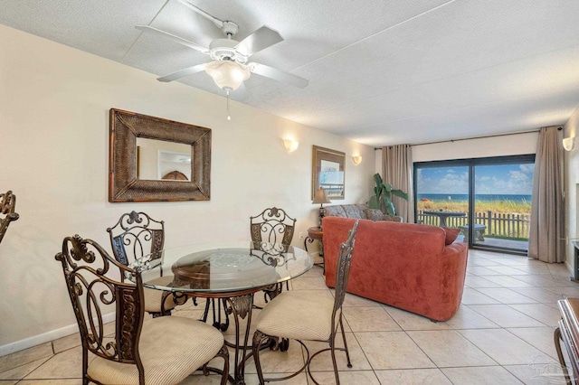 dining room featuring a ceiling fan, a textured ceiling, baseboards, and light tile patterned floors