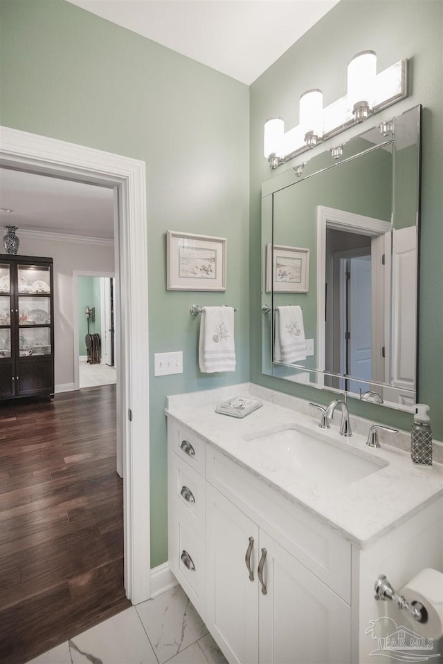 bathroom with marble finish floor, baseboards, crown molding, and vanity