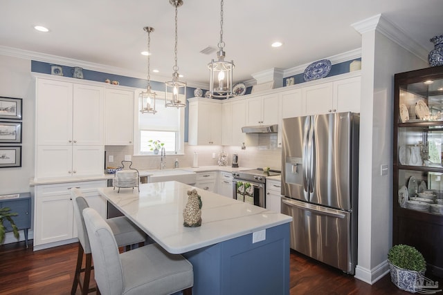 kitchen with a center island, hanging light fixtures, appliances with stainless steel finishes, a sink, and under cabinet range hood