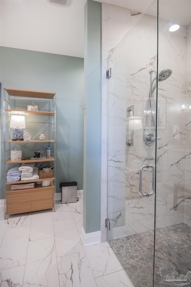 bathroom featuring marble finish floor, a marble finish shower, and baseboards