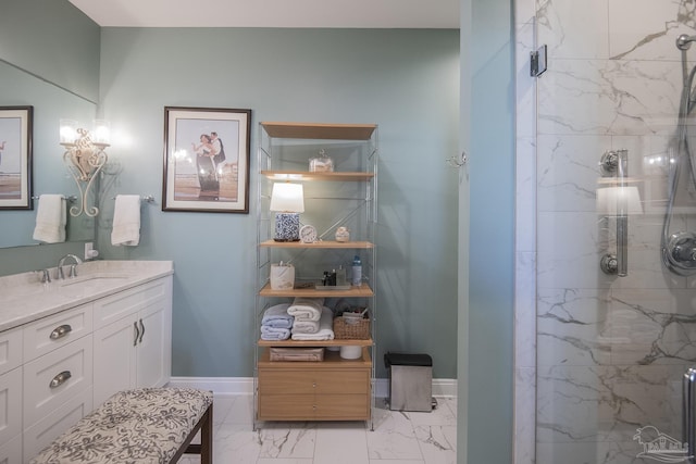 bathroom featuring marble finish floor, a marble finish shower, baseboards, and vanity