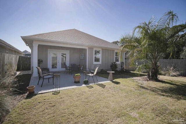 rear view of house featuring a yard, a fenced backyard, a patio, and french doors