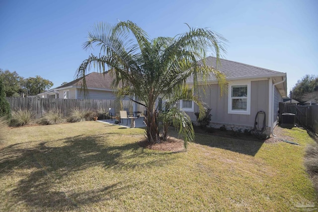 view of home's exterior with a yard, a patio, central air condition unit, board and batten siding, and fence