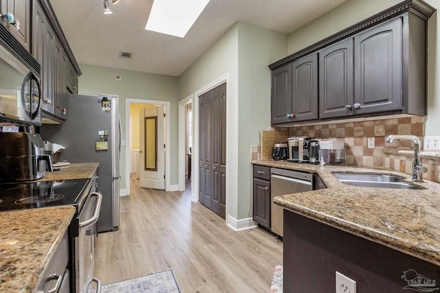 9348 Bell Ridge Dr, Pensacola, FL 32526 - kitchen featuring light stone counters, a sink, light wood finished floors, stainless steel appliances, and a skylight