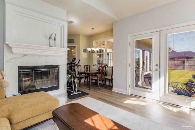 9348 Bell Ridge Dr, Pensacola, FL 32526 - living area featuring french doors, a fireplace, wood finished floors, baseboards, and a chandelier