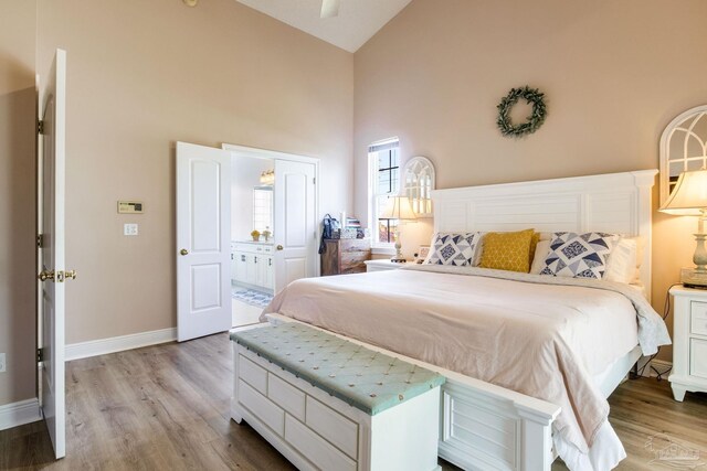 9348 Bell Ridge Dr, Pensacola, FL 32526 - bedroom featuring baseboards, ensuite bath, wood finished floors, and high vaulted ceiling