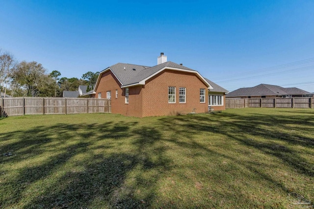 9348 Bell Ridge Dr, Pensacola, FL 32526 - rear view of house with brick siding, a fenced backyard, a lawn, and a chimney