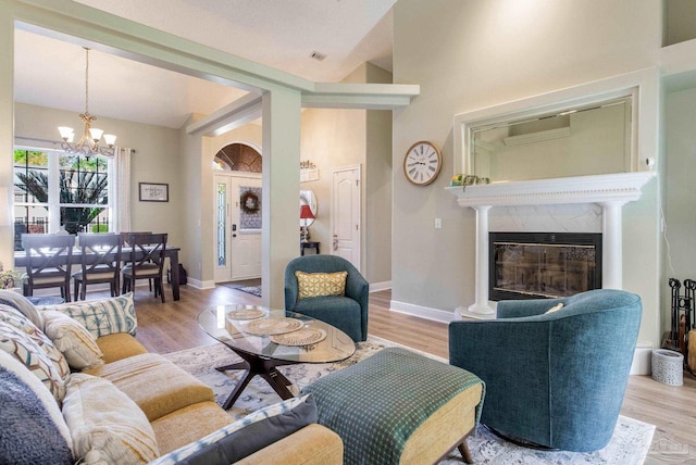 9348 Bell Ridge Dr, Pensacola, FL 32526 - living room featuring a high end fireplace, baseboards, light wood-type flooring, and a notable chandelier