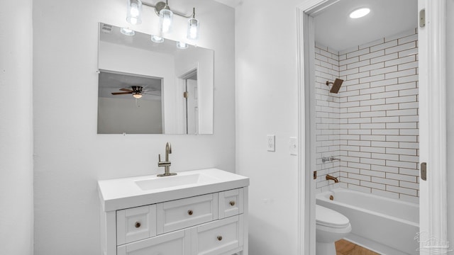 full bathroom featuring vanity, ceiling fan, toilet, and tiled shower / bath