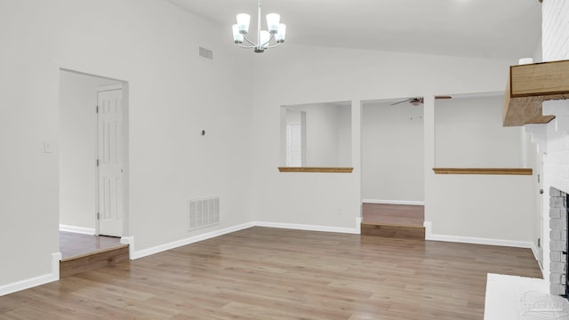 interior space featuring ceiling fan with notable chandelier, light hardwood / wood-style floors, a brick fireplace, and high vaulted ceiling