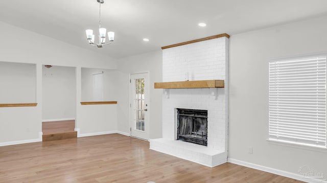 unfurnished living room with a chandelier, a fireplace, light hardwood / wood-style floors, and vaulted ceiling