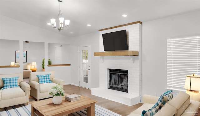 living room with a chandelier, a fireplace, wood-type flooring, and lofted ceiling