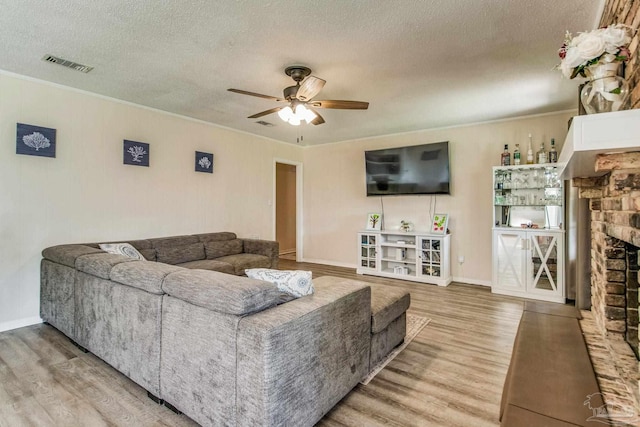 living room featuring a fireplace, wood-type flooring, a textured ceiling, and ceiling fan