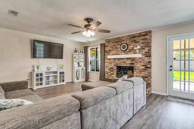 living room with a brick fireplace, hardwood / wood-style flooring, ornamental molding, and a wealth of natural light