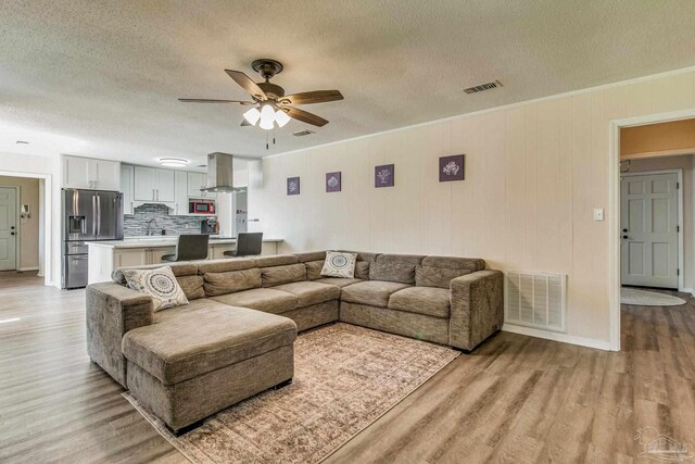 living room featuring ceiling fan, a textured ceiling, light hardwood / wood-style flooring, and sink