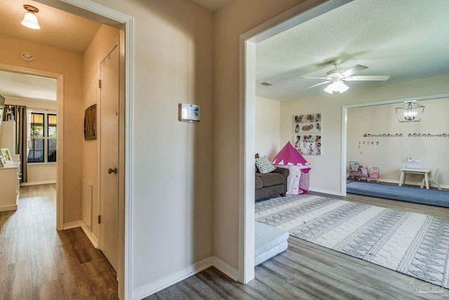 corridor with hardwood / wood-style flooring and a textured ceiling