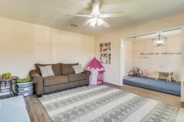 living room featuring wood-type flooring, a textured ceiling, and ceiling fan with notable chandelier