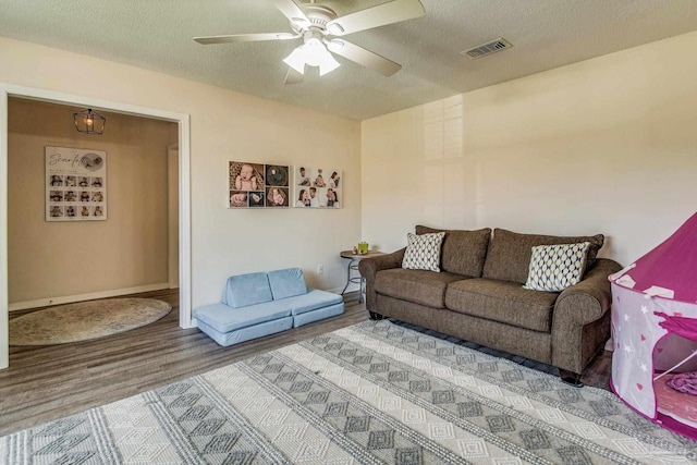 living room featuring ceiling fan, hardwood / wood-style floors, and a textured ceiling