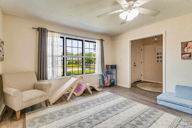 living area featuring ceiling fan, light hardwood / wood-style floors, and a textured ceiling