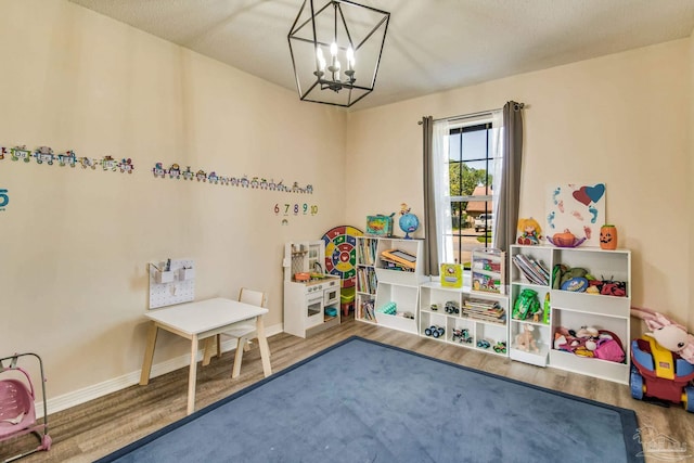 playroom featuring an inviting chandelier and hardwood / wood-style flooring