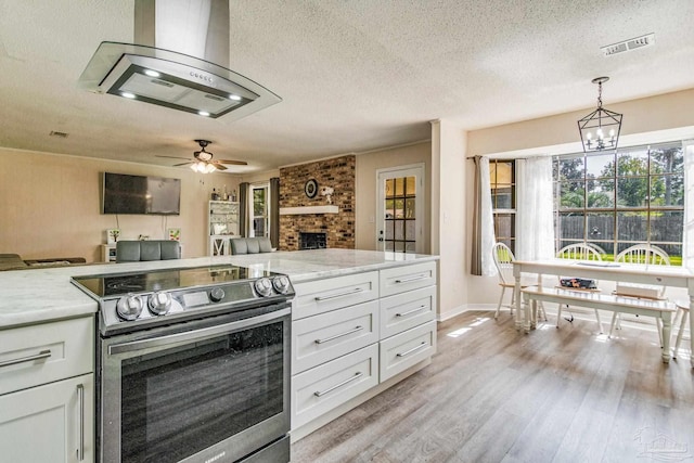 kitchen with stainless steel range with electric cooktop, decorative light fixtures, light hardwood / wood-style flooring, and white cabinetry