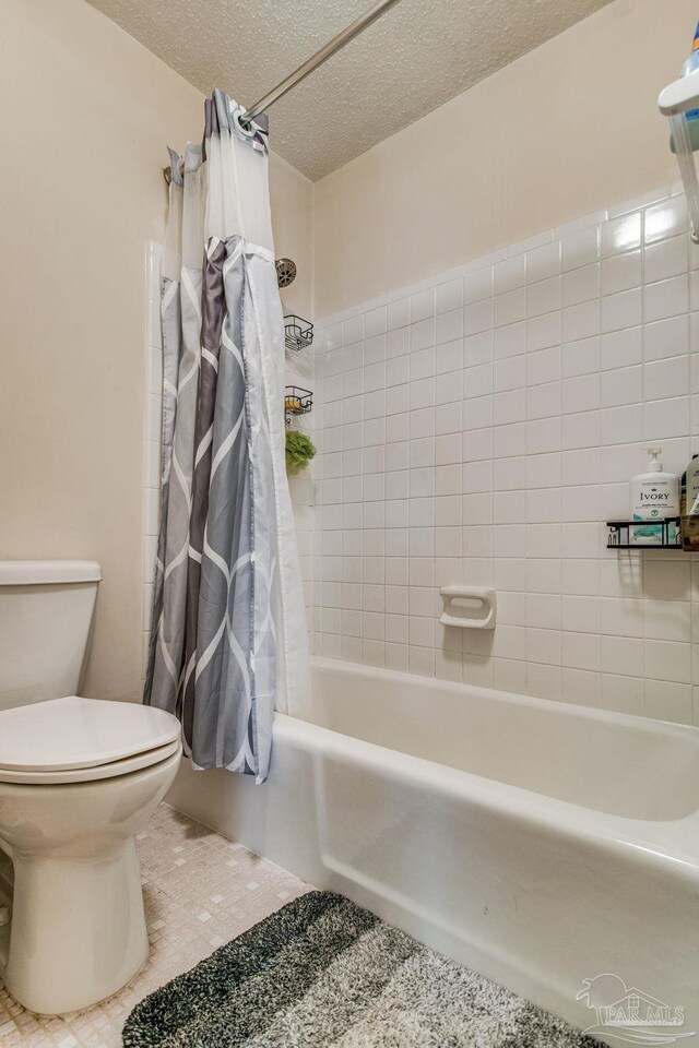 bathroom featuring shower / tub combo, tile patterned flooring, toilet, and a textured ceiling