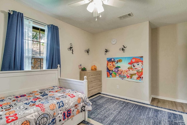 bedroom featuring hardwood / wood-style flooring, a textured ceiling, and ceiling fan