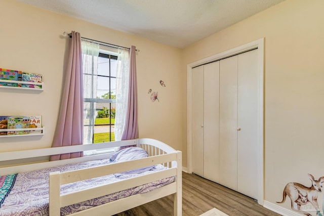 bedroom with a textured ceiling, light hardwood / wood-style flooring, and a closet