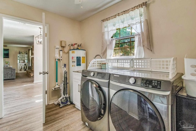 clothes washing area with water heater, light wood-type flooring, and washing machine and clothes dryer