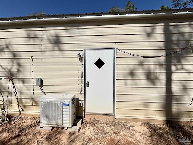 view of exterior entry featuring ac unit and metal roof