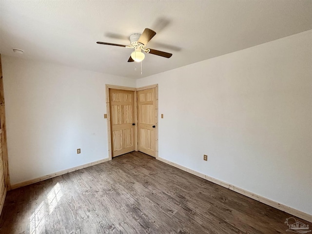 spare room with wood finished floors, a ceiling fan, and baseboards