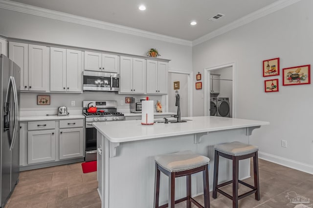 3209 Mountain Laurel Trl, Cantonment, FL 32533 - kitchen with appliances with stainless steel finishes, independent washer and dryer, a sink, ornamental molding, and a breakfast bar