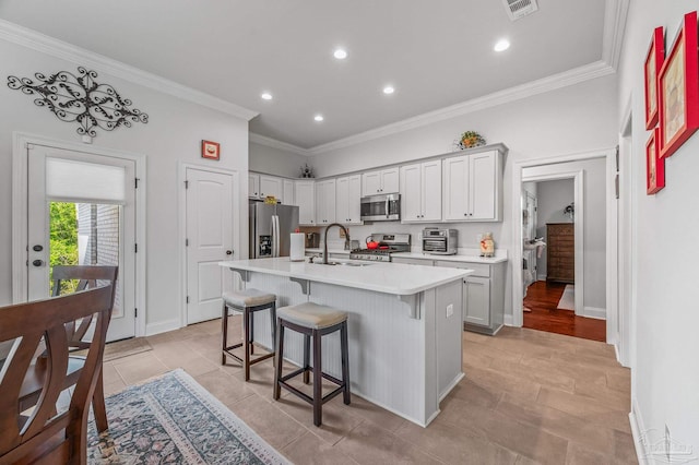 3209 Mountain Laurel Trl, Cantonment, FL 32533 - kitchen featuring stainless steel appliances, a breakfast bar area, light countertops, a center island with sink, and ornamental molding