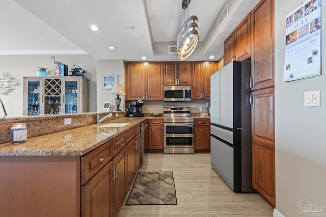 616 Lost Key Dr Unit 902A, Perdido Key, FL 32507 - kitchen featuring stainless steel appliances, a sink, light wood-type flooring, brown cabinets, and light stone countertops