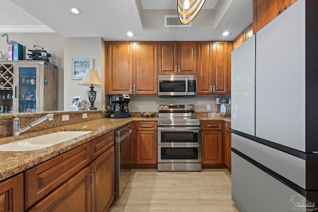 616 Lost Key Dr Unit 902A, Perdido Key, FL 32507 - kitchen with stainless steel appliances, a sink, recessed lighting, brown cabinets, and light stone counters