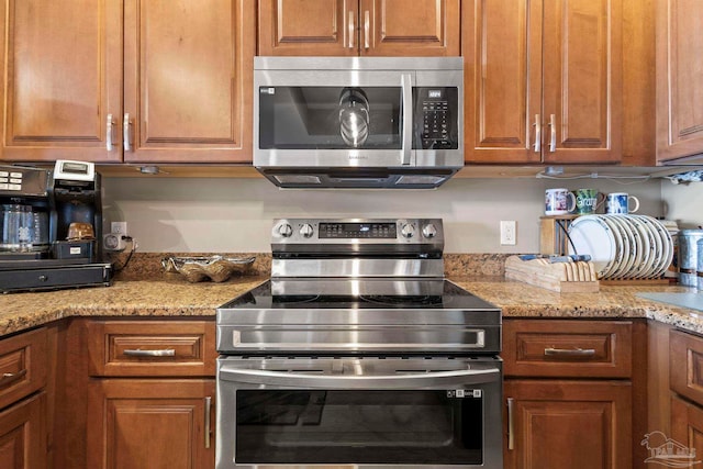 616 Lost Key Dr Unit 902A, Perdido Key, FL 32507 - kitchen with appliances with stainless steel finishes, brown cabinetry, and light stone counters