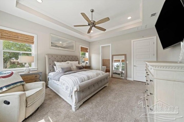 carpeted bedroom with a tray ceiling, ceiling fan, and crown molding