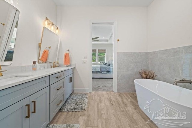 bathroom featuring a bathtub, vanity, tile walls, and hardwood / wood-style flooring