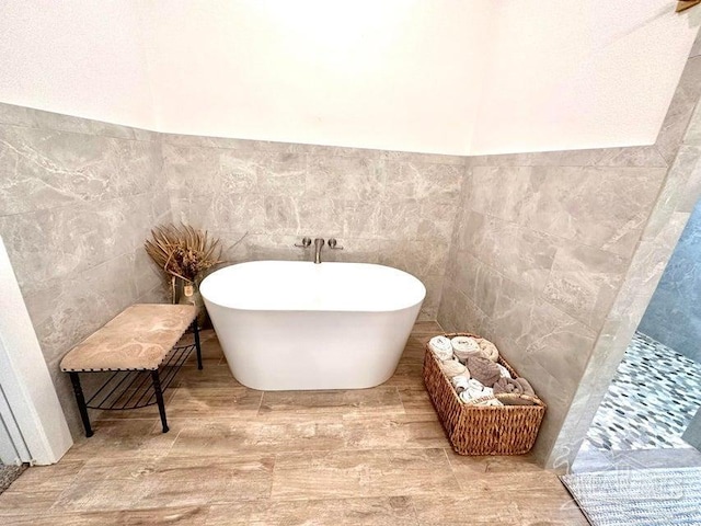 bathroom featuring a washtub, hardwood / wood-style floors, and tile walls